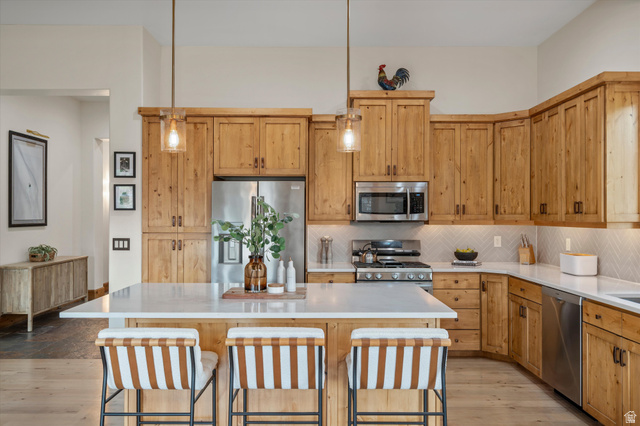 4892 Eagle Rdg Drive Eden, UT 84310 - Photo 11 of 39 Kitchen featuring natural wood cabinetry, stainless steel appliances, and a central island with a light-toned countertop
