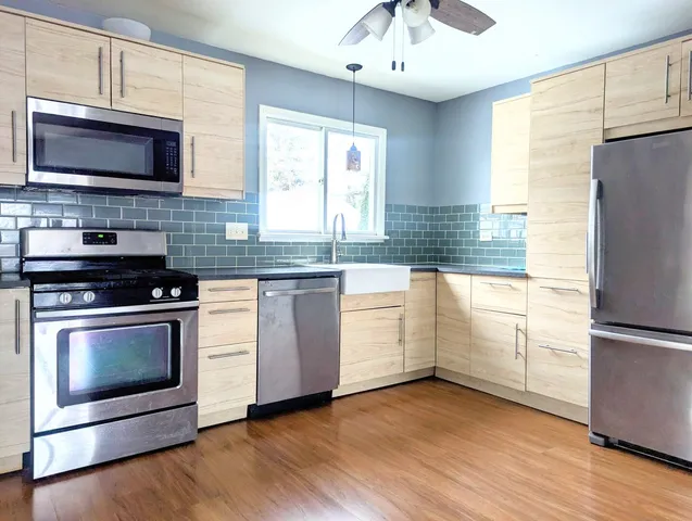 a kitchen with granite countertop wooden floors and stainless steel appliances