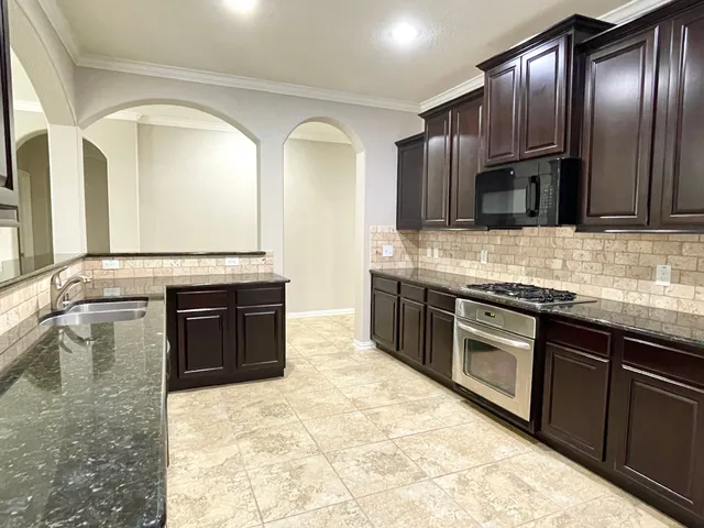 a large kitchen with granite countertop stainless steel appliances and wooden cabinets