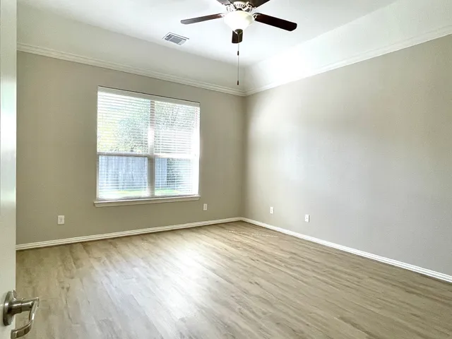 an empty room with wooden floor chandelier fan and windows