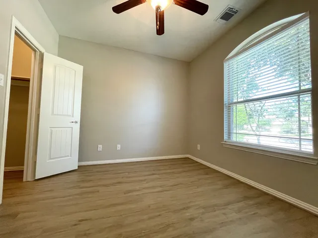 an empty room with wooden floor cabinet and windows