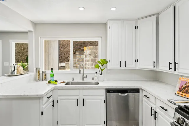 a kitchen with stainless steel appliances granite countertop a sink a counter space and a window