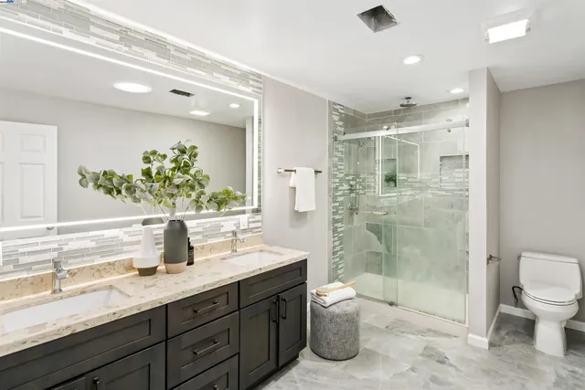 a bathroom with a granite countertop sink mirror and toilet