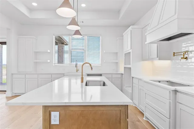 a kitchen with stainless steel appliances granite countertop a sink a stove and a wooden floors