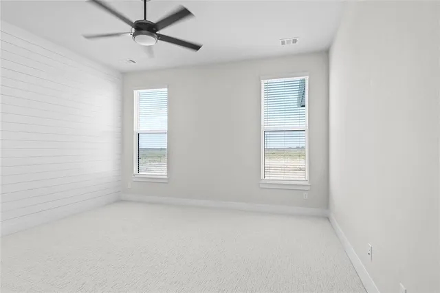an empty room with a window and a fan