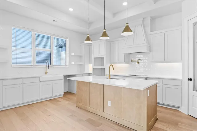 a kitchen with a sink a window and white cabinets