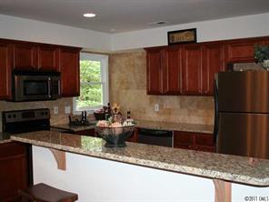 3077 Point Clear Drive Tega Cay, SC 29708 - Photo 2 of 5 a kitchen with granite countertop wooden cabinets a refrigerator and a sink