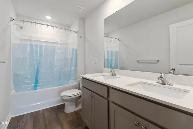 a bathroom with a sink a toilet a mirror and shower