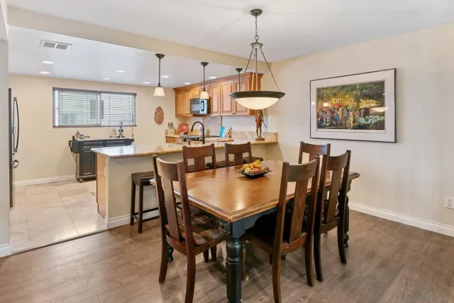 a dining room with stainless steel appliances a table chairs and a kitchen view