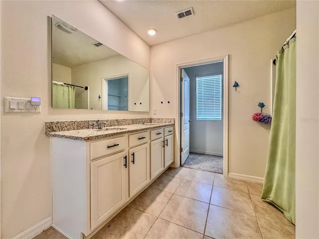 a spacious bathroom with a granite countertop sink and a mirror