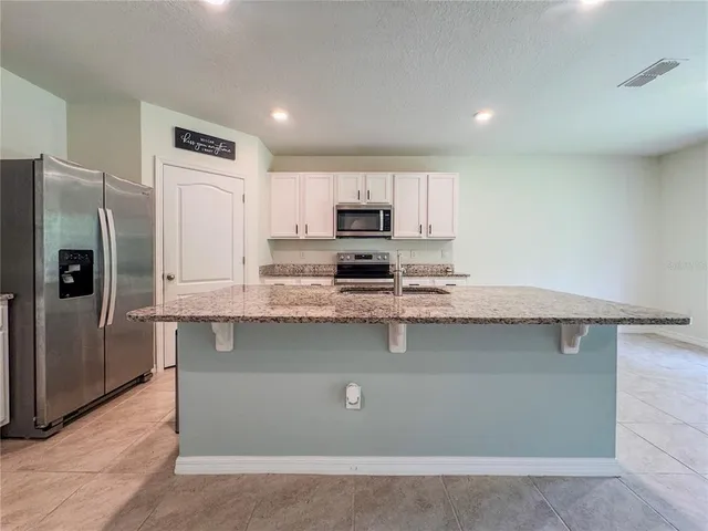 a kitchen with stainless steel appliances granite countertop a stove a sink and a refrigerator