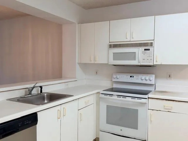 a kitchen with cabinets appliances a sink and a counter top