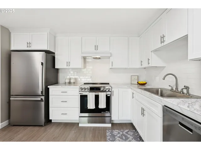 a kitchen with stainless steel appliances granite countertop a refrigerator stove a sink and white cabinets