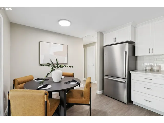 a kitchen with stainless steel appliances granite countertop a dining table chairs and refrigerator