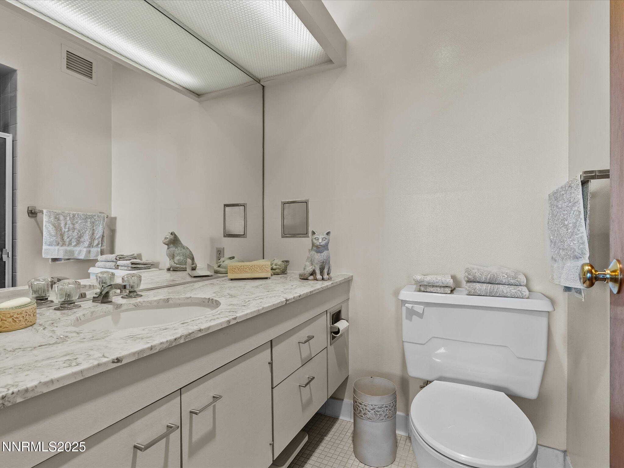 100 North Arlington Avenue, Unit 20J Reno, NV 89501 - Photo 12 of 17 a bathroom with a granite countertop toilet sink and mirror