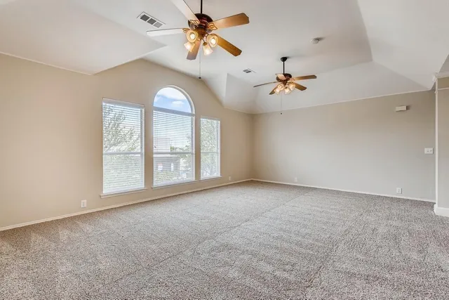 an empty room with chandelier fan and windows