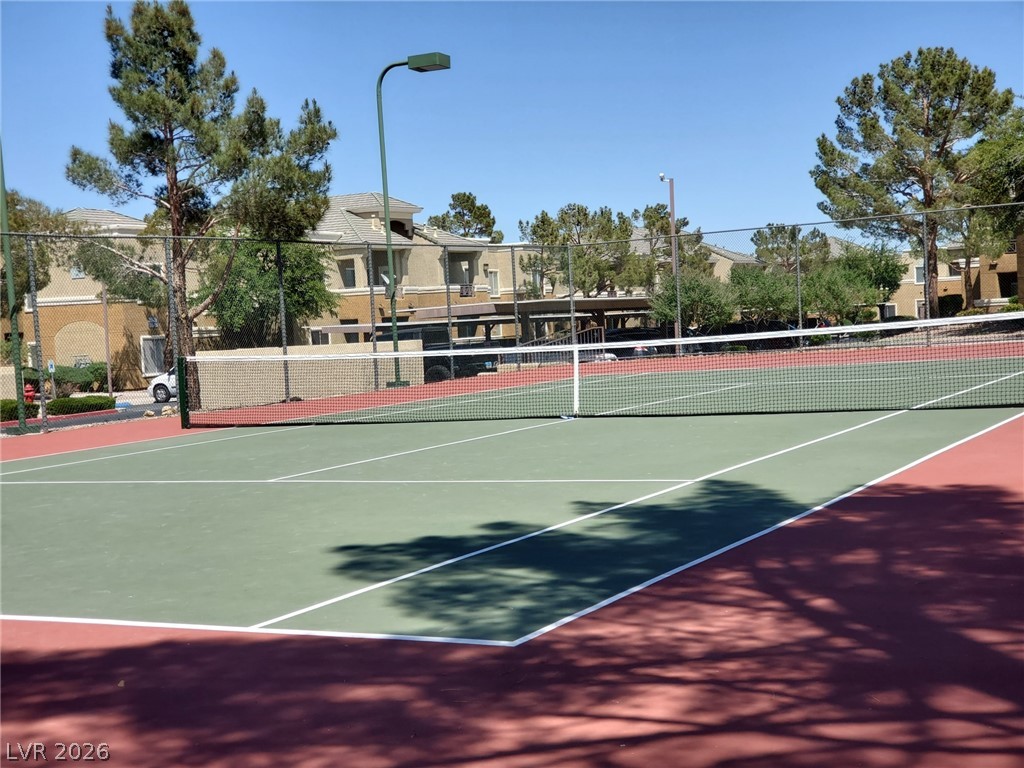 8070 West Russell Road, Unit 1123 Las Vegas, NV 89113 - Photo 3 of 5 Enjoy a game on the meticulously maintained tennis court, set against a backdrop of mature trees and community buildings.