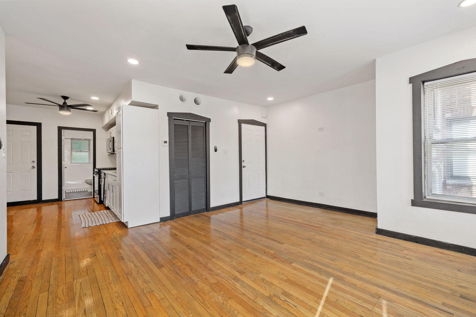 7202 South Indiana Avenue, Unit 1F Chicago, IL 60619 - Photo 4 of 7 a view of a livingroom with a ceiling fan wooden floor and a window