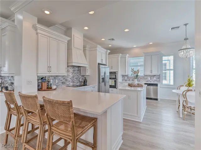 a large kitchen with kitchen island white cabinets and stainless steel appliances