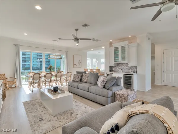 a living room with furniture large windows and wooden floor