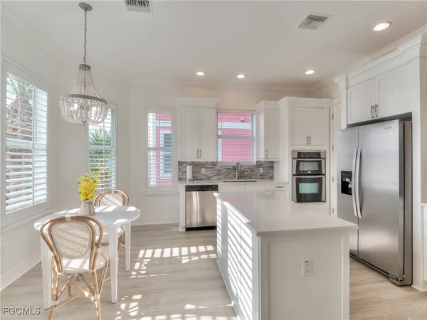 a kitchen with granite countertop stainless steel appliances a refrigerator a stove a sink a dining table and chairs