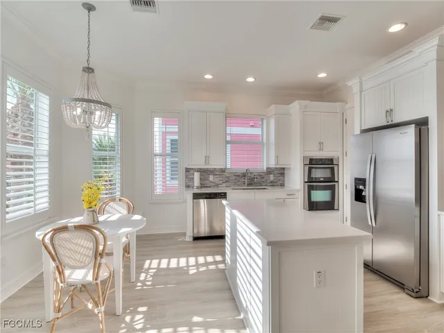 a kitchen with granite countertop stainless steel appliances a refrigerator a stove a sink a dining table and chairs