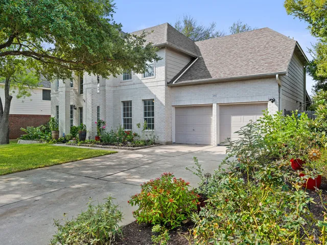 a front view of a house with a garden and trees