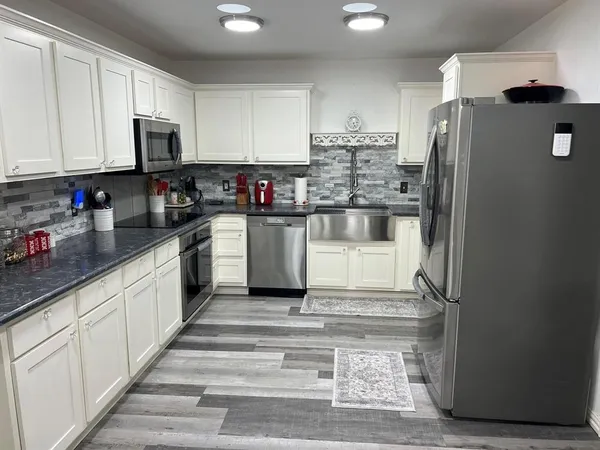 a kitchen with granite countertop a refrigerator stove and microwave