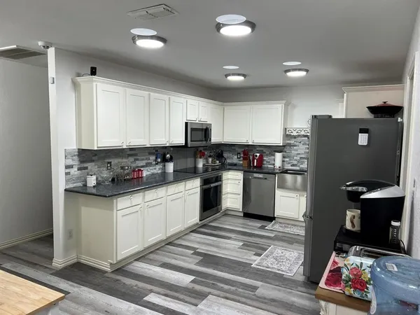a kitchen with granite countertop a refrigerator stove top oven and sink