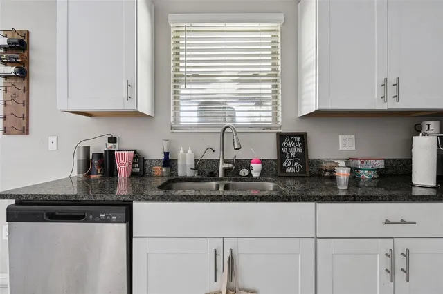 a kitchen with a sink dishwasher a stove and white cabinets with wooden floor