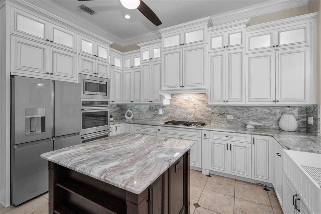 1227 Toscano Drive Trinity, FL 34655 - Photo 15 of 99 a kitchen with kitchen island granite countertop a wooden cabinets and white appliances