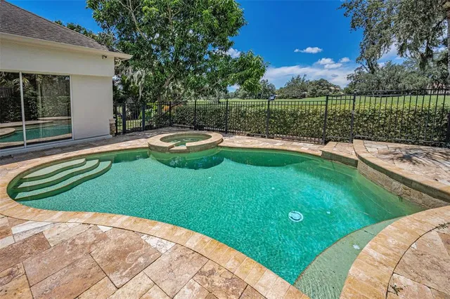 a view of a backyard with swimming pool and a small yard