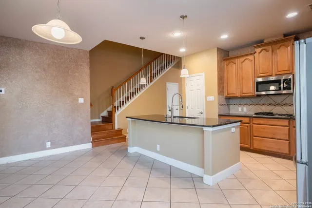 a kitchen with stainless steel appliances granite countertop a refrigerator a stove top oven a sink and dishwasher