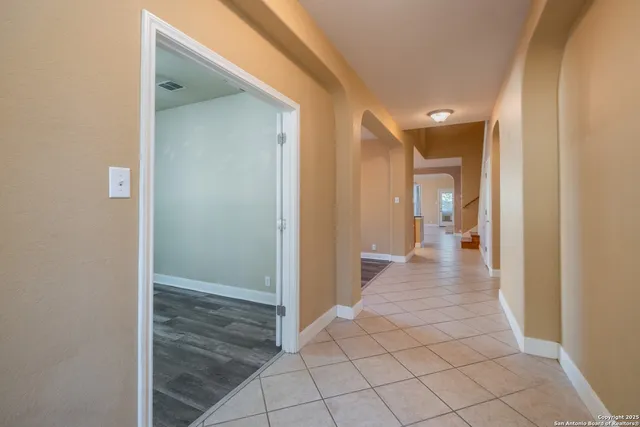 a view of an empty room with window and chandelier fan