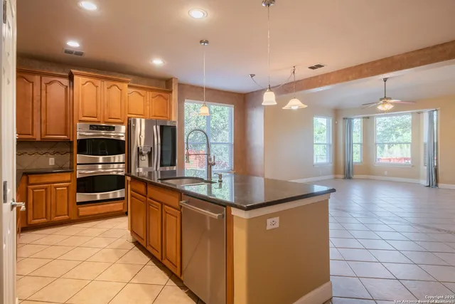 a kitchen with stainless steel appliances granite countertop a refrigerator and a stove top oven