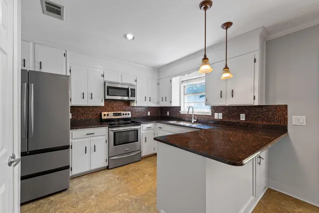 a kitchen with a sink a stove a refrigerator and chairs