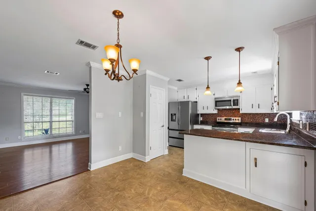 a kitchen with kitchen island granite countertop a sink a counter space appliances and cabinets