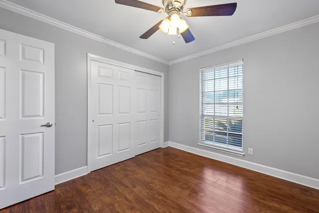 an empty room with wooden floor chandelier fan and windows