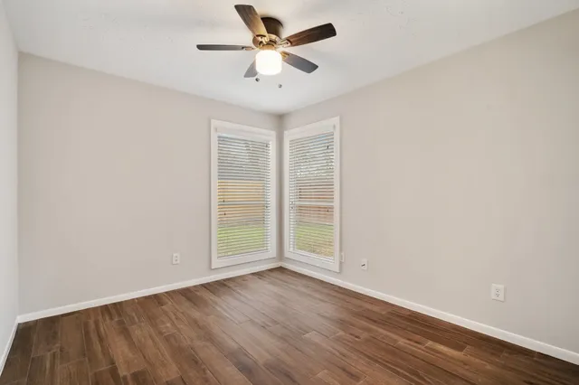 an empty room with wooden floor and ceiling fan