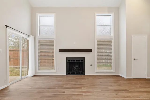 an empty room with windows and fireplace
