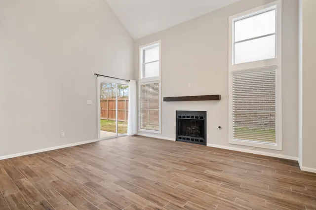 an empty room with wooden floor fireplace and windows