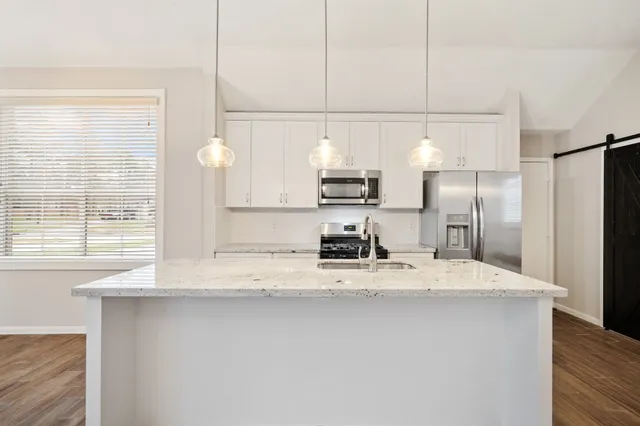 a kitchen with kitchen island granite countertop a sink a counter space and stainless steel appliances
