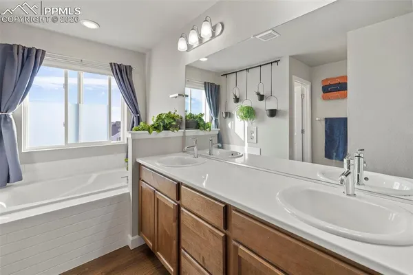 a bathroom with a sink double vanity granite tub and a large mirror