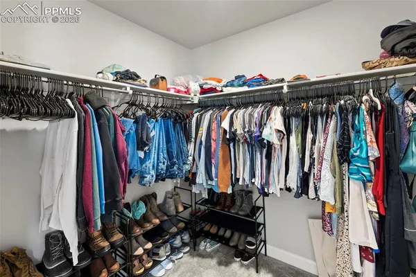a view of walk in closet with clothes and shoes