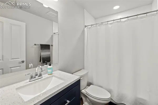 a bathroom with a sink a toilet a mirror and shower curtain