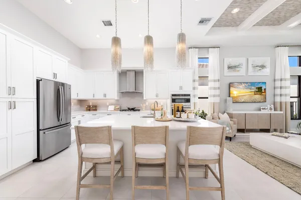 a kitchen with granite countertop a refrigerator a stove a dining table and chairs with wooden floor