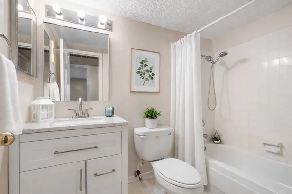 a bathroom with a sink a toilet a mirror a vanity a bath tub and shower