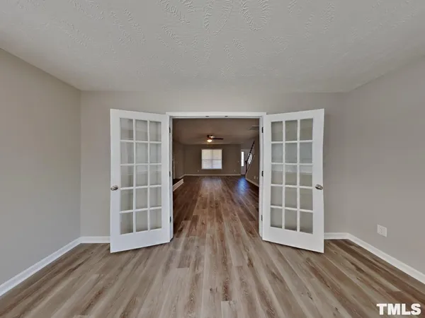 an empty room with wooden floor and windows