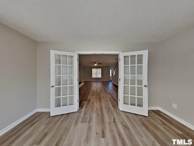 an empty room with wooden floor and windows