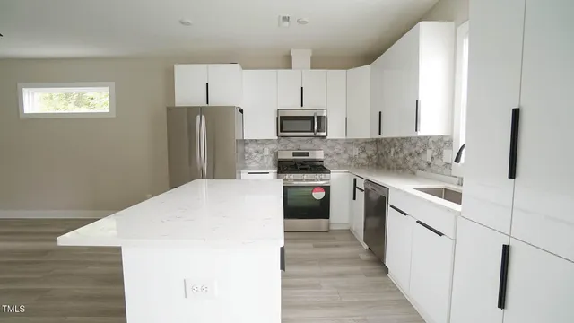 a kitchen with granite countertop a refrigerator stove top oven and sink